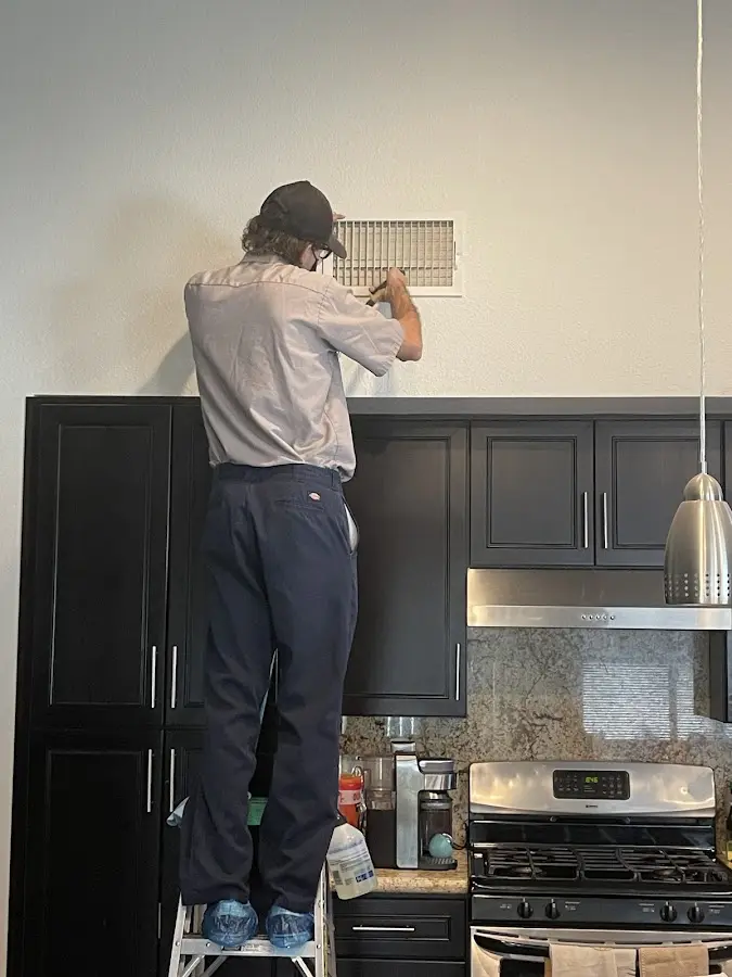 Technician inspecting an air vent during HVAC service in Freehold